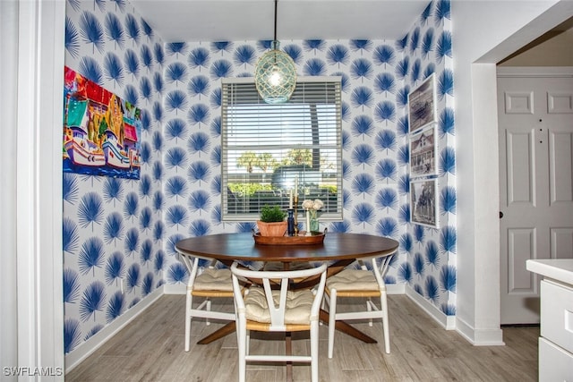 dining room featuring baseboards, light wood finished floors, and wallpapered walls