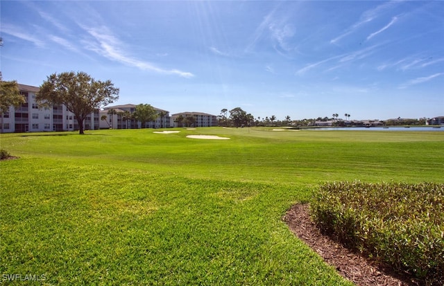 surrounding community with a water view, view of golf course, and a lawn