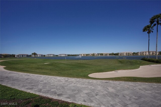 surrounding community featuring view of golf course and a lawn