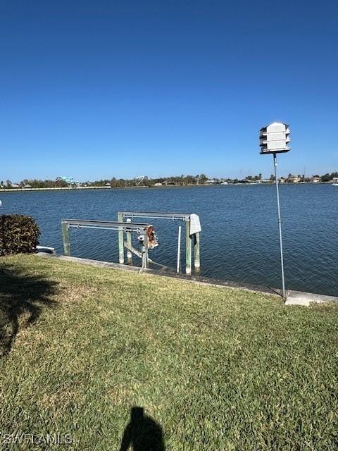 view of dock featuring a water view and a yard