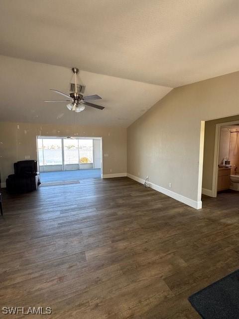 unfurnished living room with a ceiling fan, baseboards, vaulted ceiling, and dark wood-type flooring