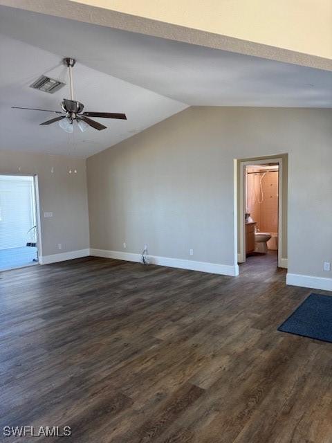 unfurnished living room featuring dark wood-style flooring, a ceiling fan, visible vents, vaulted ceiling, and baseboards