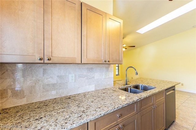 kitchen featuring a sink, baseboards, stainless steel dishwasher, decorative backsplash, and light stone countertops