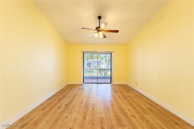 spare room with lofted ceiling, light wood-style floors, baseboards, and a ceiling fan