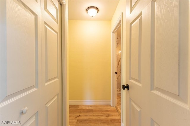 corridor with baseboards and light wood-style floors