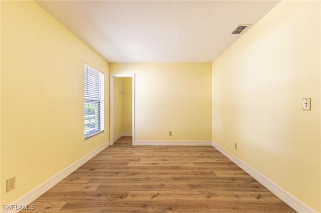 unfurnished room featuring light wood-type flooring, visible vents, and baseboards