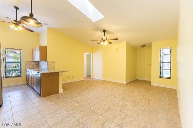 kitchen with lofted ceiling with skylight, ceiling fan, stainless steel appliances, and a sink