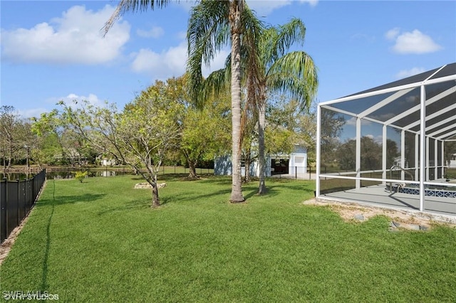 view of yard with fence, a water view, and glass enclosure