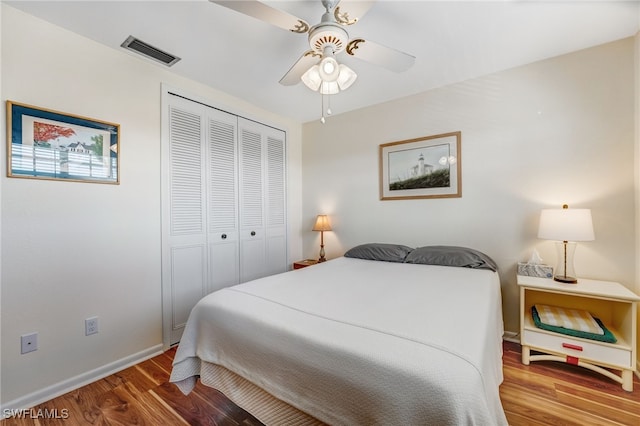 bedroom featuring ceiling fan, wood finished floors, visible vents, baseboards, and a closet