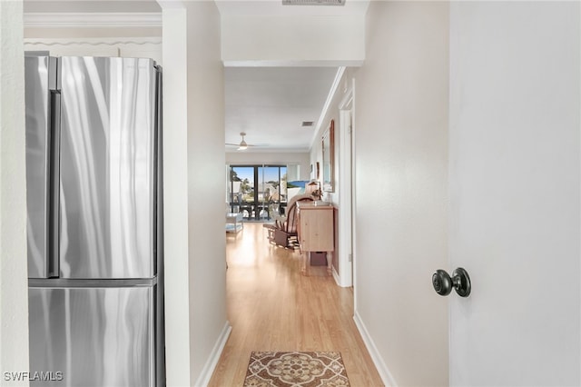 hall featuring baseboards, crown molding, visible vents, and light wood finished floors