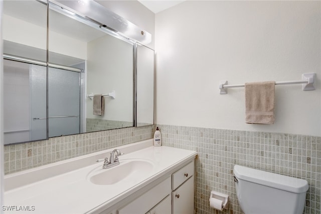 bathroom featuring tile walls, a wainscoted wall, vanity, and toilet