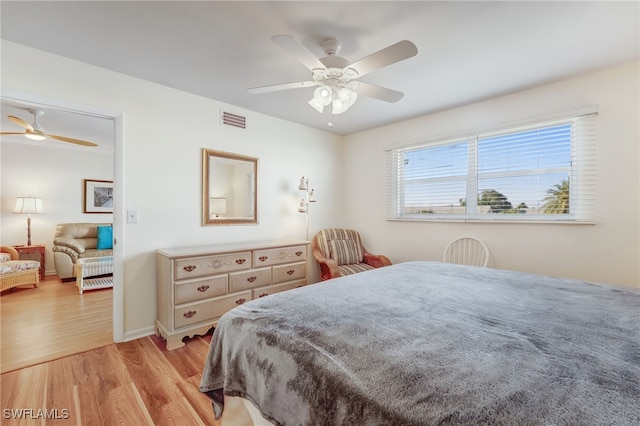 bedroom featuring light wood-style floors, baseboards, visible vents, and a ceiling fan