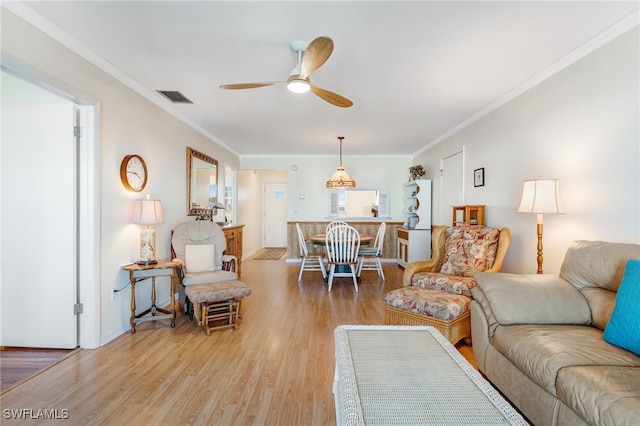 living room with ceiling fan, light wood-type flooring, visible vents, and crown molding