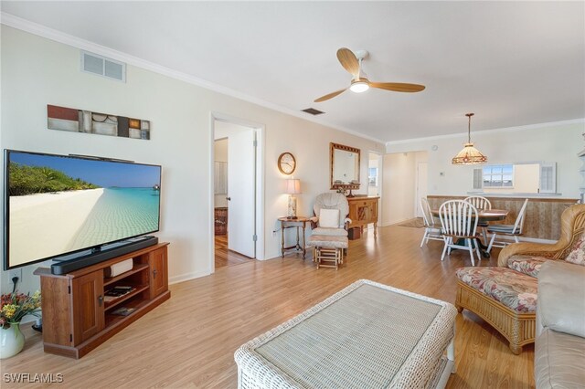 living area with ornamental molding, ceiling fan, light wood-style flooring, and visible vents