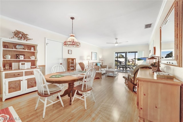 dining room with ornamental molding, light wood-type flooring, visible vents, and ceiling fan