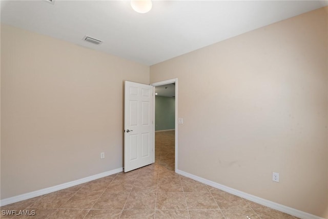 empty room featuring light tile patterned flooring, visible vents, and baseboards