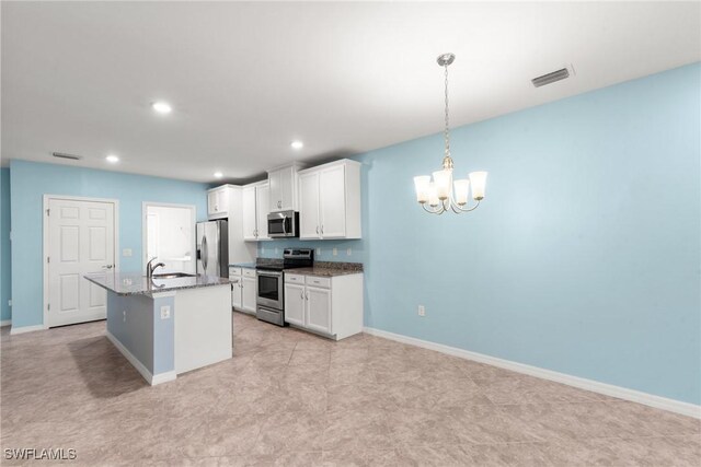 kitchen featuring stainless steel appliances, visible vents, baseboards, white cabinetry, and a center island with sink