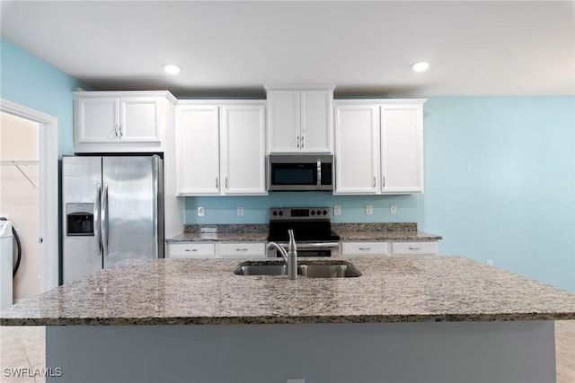 kitchen featuring stainless steel appliances, light stone counters, a sink, and white cabinets