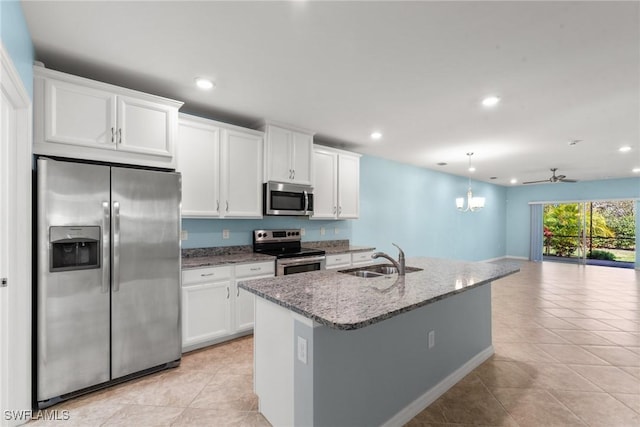 kitchen with stone countertops, white cabinets, open floor plan, stainless steel appliances, and a sink