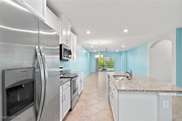 kitchen featuring light tile patterned floors, an island with sink, appliances with stainless steel finishes, white cabinetry, and a sink