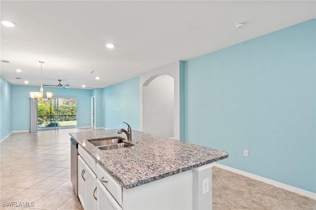 kitchen featuring arched walkways, a sink, white cabinets, open floor plan, and an island with sink