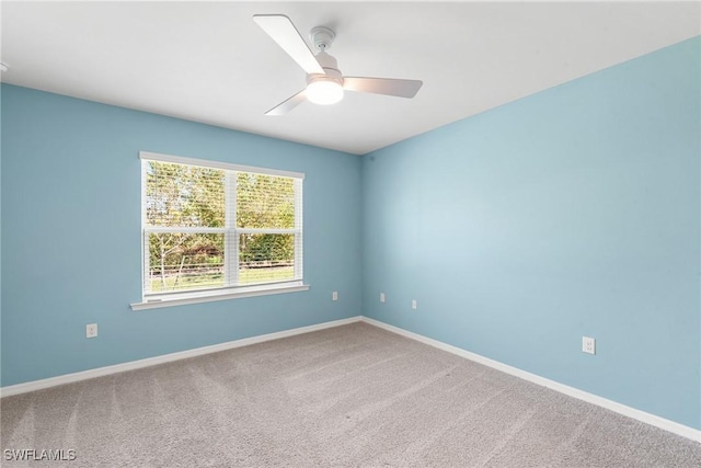 carpeted spare room featuring ceiling fan and baseboards