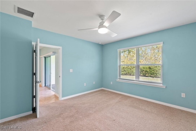 empty room with carpet floors, baseboards, visible vents, and a ceiling fan