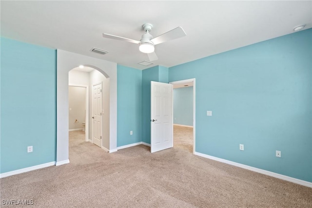 unfurnished bedroom featuring arched walkways, carpet floors, a ceiling fan, visible vents, and baseboards