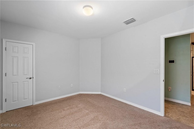 carpeted empty room featuring baseboards and visible vents