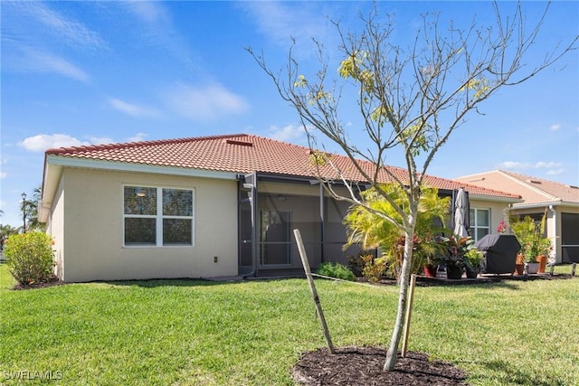 rear view of house with a tile roof, a lawn, and stucco siding