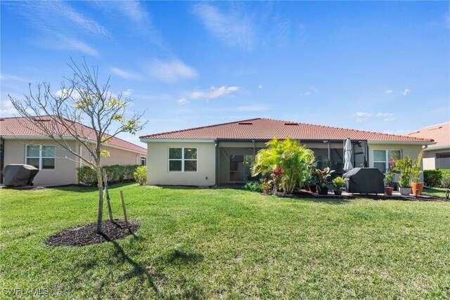 back of property featuring a yard, a tiled roof, and stucco siding