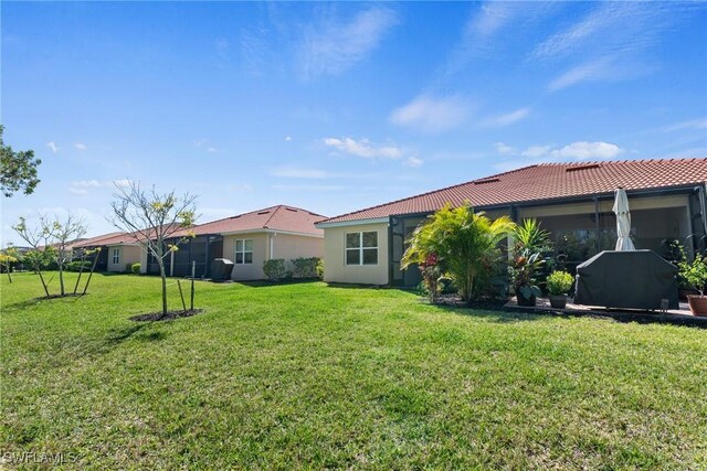 back of property with a tile roof, a yard, and stucco siding