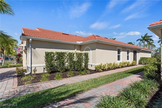 view of side of property featuring a tiled roof and stucco siding