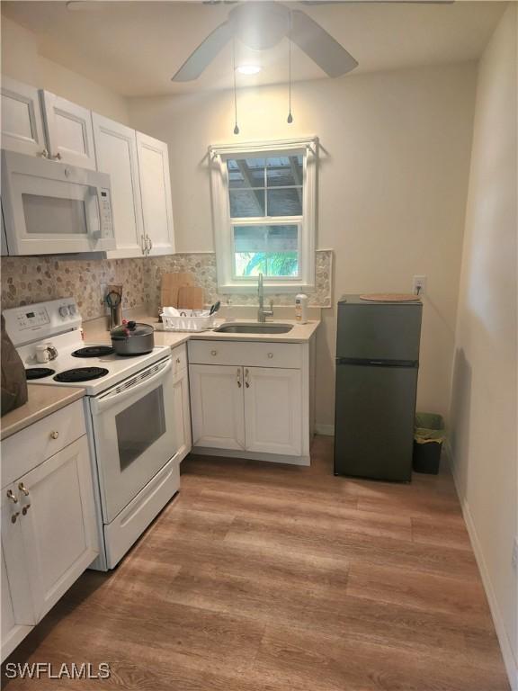 kitchen with light wood-style floors, white appliances, white cabinetry, and a sink