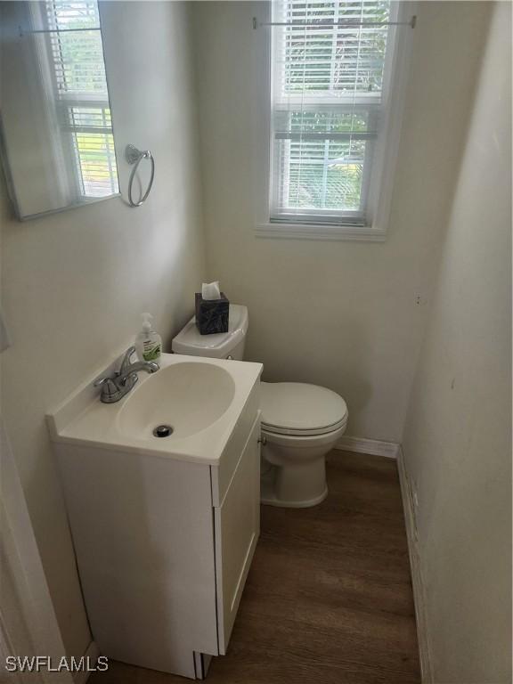 bathroom with toilet, baseboards, wood finished floors, and vanity