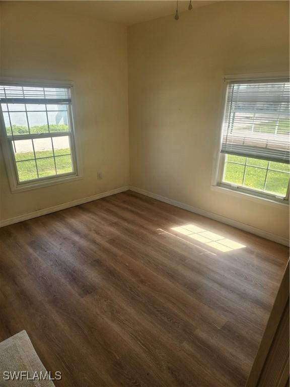 spare room with dark wood-style flooring and baseboards