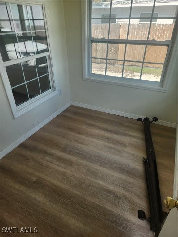 unfurnished room with dark wood finished floors and baseboards