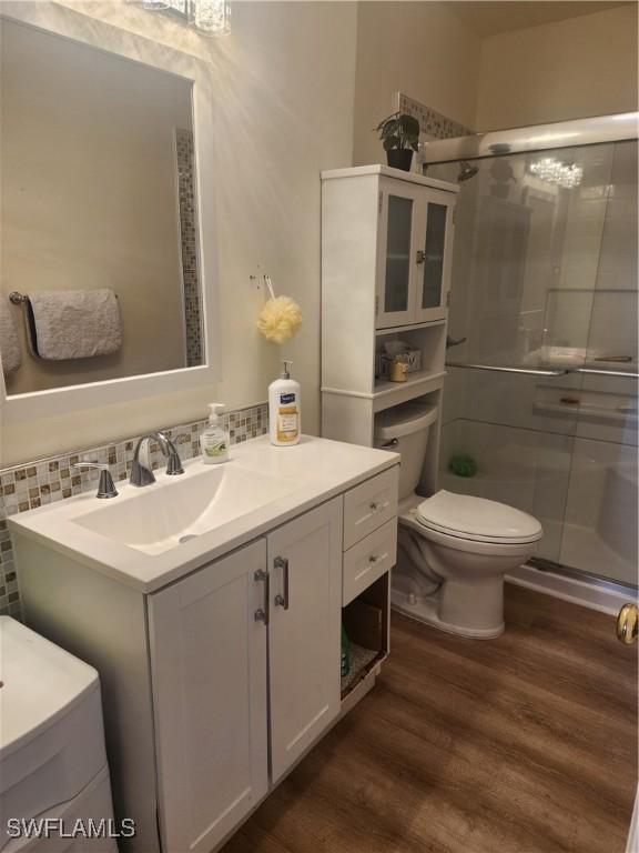 full bath with a stall shower, vanity, toilet, and wood finished floors