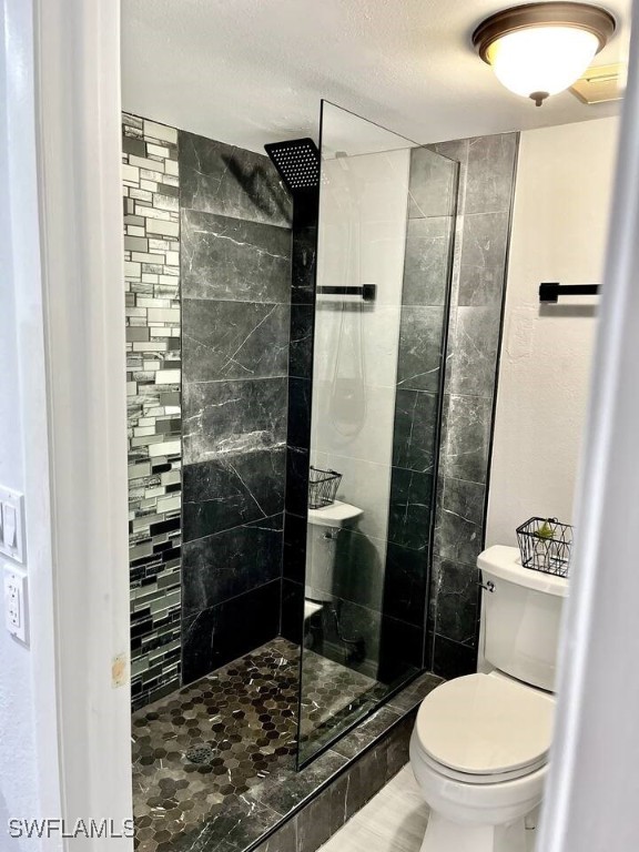 bathroom with toilet, walk in shower, and a textured ceiling