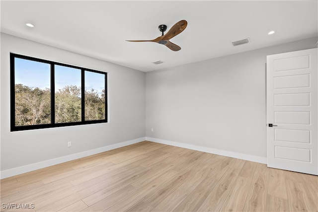 spare room with light wood-type flooring, baseboards, visible vents, and a ceiling fan