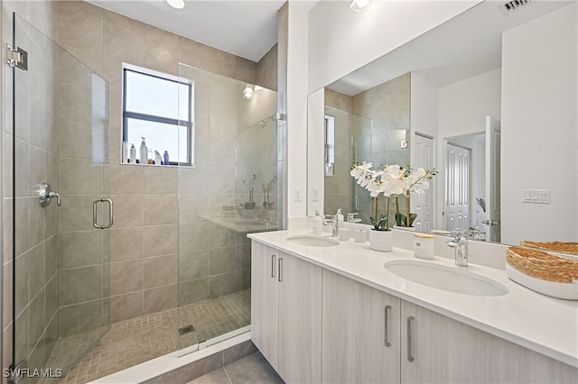 bathroom with double vanity, a stall shower, tile patterned floors, and a sink