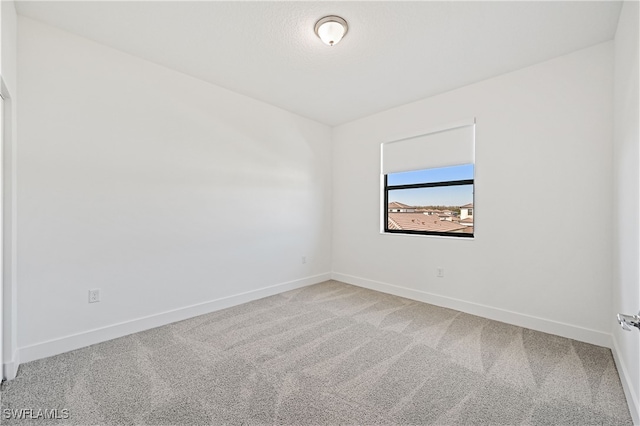 carpeted empty room featuring baseboards