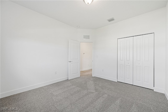 unfurnished bedroom with a closet, visible vents, baseboards, and carpet floors