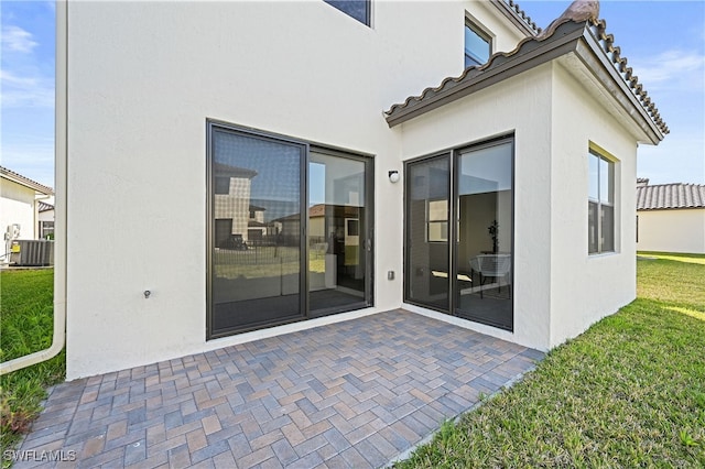 exterior space featuring cooling unit, a yard, stucco siding, a tiled roof, and a patio area