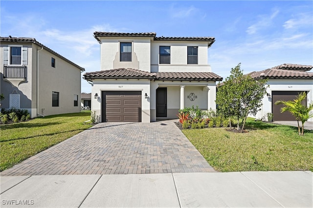 mediterranean / spanish house with a front yard, a tiled roof, decorative driveway, and stucco siding