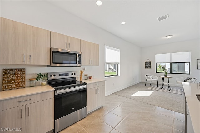 kitchen with visible vents, light brown cabinetry, appliances with stainless steel finishes, light countertops, and light tile patterned floors