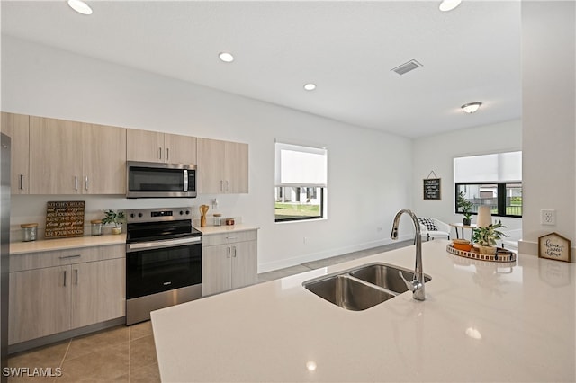 kitchen with visible vents, light brown cabinetry, appliances with stainless steel finishes, light tile patterned flooring, and a sink