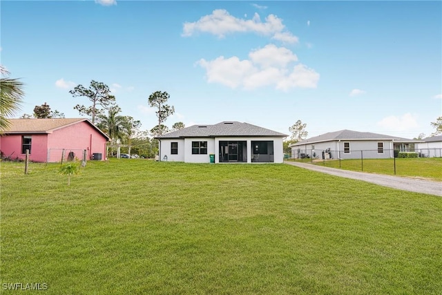 rear view of property featuring a lawn and fence