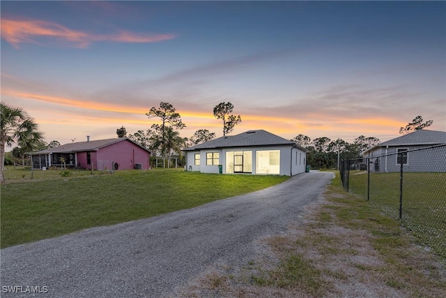 view of front of property with a lawn, driveway, and fence