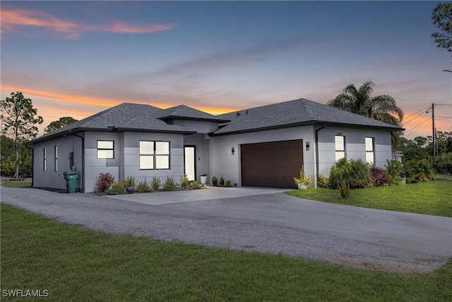 view of front of house with a garage, a shingled roof, concrete driveway, a lawn, and stucco siding